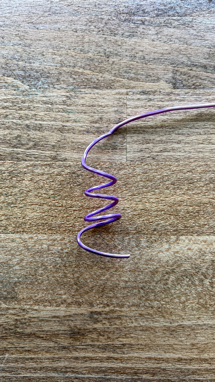 Purple craft wire twisted into a coil.