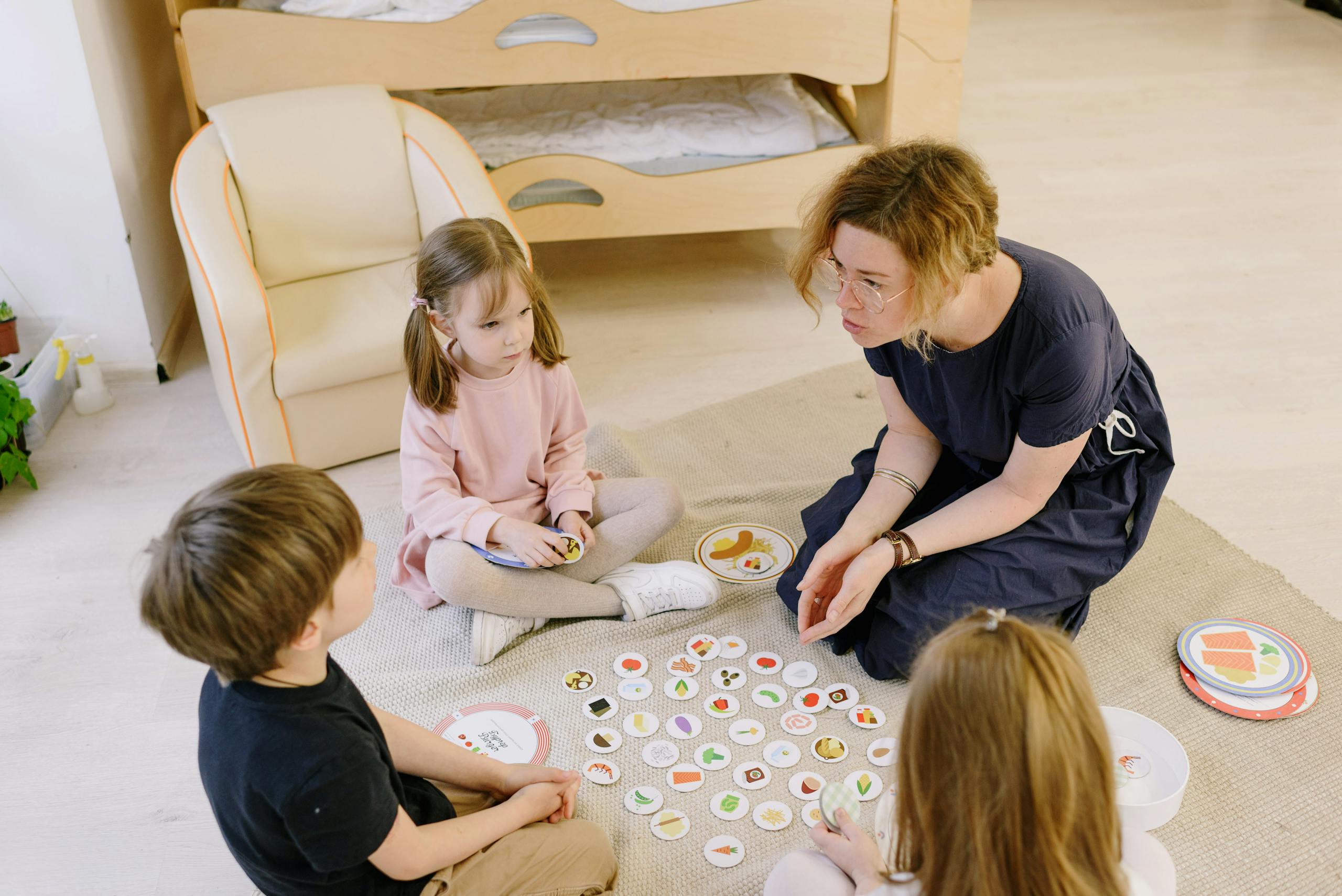 Mother and Children Sitting on the Floor while Playing Round Shaped Cards
